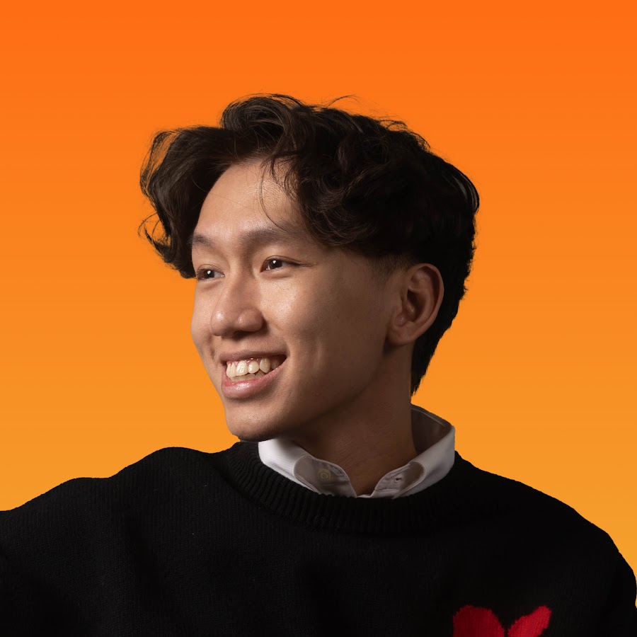 Tuan Le smiling against an orange background